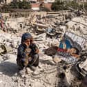 ALEPPO, SYRIA - FEBRUARY 28: A child watches as Jasmine, 23 years old, paints amidst the rubble in the city of Jindires on February 28, 2023 near Aleppo, Syria. Jasmine lives in Afrin, a city near Jindires. Her paintings will be sold at auction with the proceeds to be donated to help the earthquake victims. A 7.8-magnitude earthquake hit near Gaziantep, Turkey in the early hours of February 6, followed by another 7.5-magnitude tremor just after midday. According to locals, almost 1,400 people died, and the city was badly damaged due to the earthquake. The quakes caused widespread destruction in southern Turkey and northern Syria and has killed more than 40,000 people. (Photo by Abdulmonam Eassa/Getty Images)