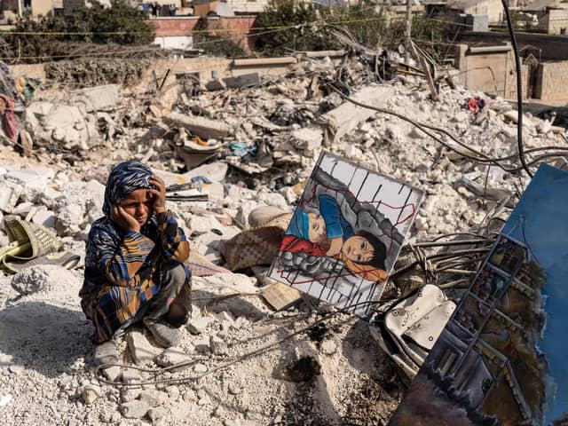 ALEPPO, SYRIA - FEBRUARY 28: A child watches as Jasmine, 23 years old, paints amidst the rubble in the city of Jindires on February 28, 2023 near Aleppo, Syria. Jasmine lives in Afrin, a city near Jindires. Her paintings will be sold at auction with the proceeds to be donated to help the earthquake victims. A 7.8-magnitude earthquake hit near Gaziantep, Turkey in the early hours of February 6, followed by another 7.5-magnitude tremor just after midday. According to locals, almost 1,400 people died, and the city was badly damaged due to the earthquake. The quakes caused widespread destruction in southern Turkey and northern Syria and has killed more than 40,000 people. (Photo by Abdulmonam Eassa/Getty Images)