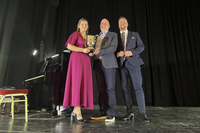 On the left is Cliodhan Regan pictured receiving her winner’s cup on the stage of St Columb’s Hall at last year’s Derry Feis. Pictured far right is Darren Hargan who adjudicated at the feis in 2025.
