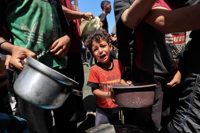 A child cries as Palestinians gather to receive a hot meal in Gaza on May 24, 2025. (Photo by EYAD BABA/AFP via Getty Images)