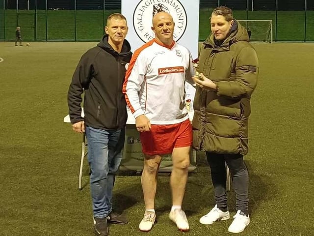 Seamus Mahon, father of Caitlin McLaughlin, collecting his participation trophy for his team and finalists Caitlin's Army from Ruaidhrí Higgins. Colly McLaughlin of GCR is also pictured.