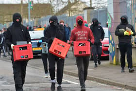 Masked youths what appear to be crates of petrol bombs in Creggan on Monday afternoon.  Photo: George Sweeney