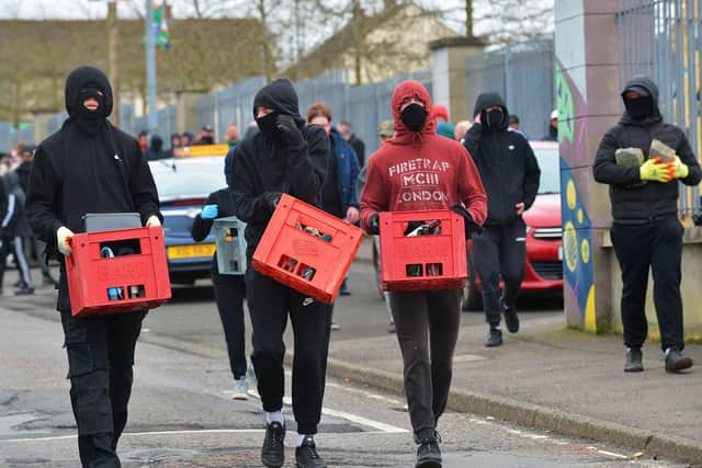 Masked youths what appear to be crates of petrol bombs in Creggan on Monday afternoon. Photo: George Sweeney