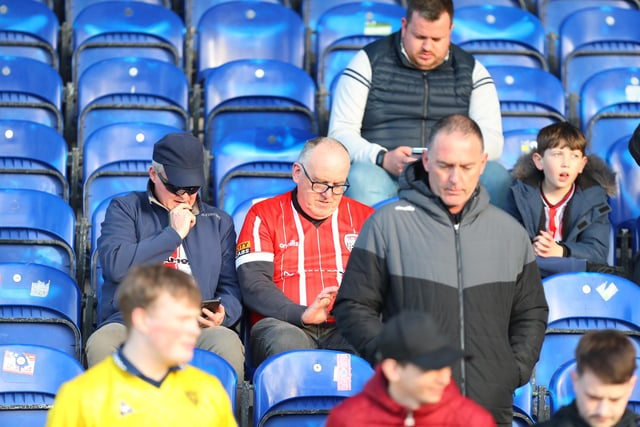 These Derry City fans check their phones for the scores around the grounds.