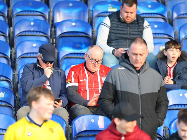 These Derry City fans check their phones for the scores around the grounds.
