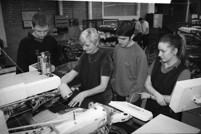 Marie McNulty, one of the Training Instructors, demonstrates how an automatic pocket attach machine operates to trainees Alan Robinson, Gerald Hutchman and Emma Goodie.