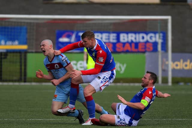 Institute ‘s Oisin Devlin is fouled by Linfield pair Ben Hall and Jamie Mulgrew. Photo: George Sweeney