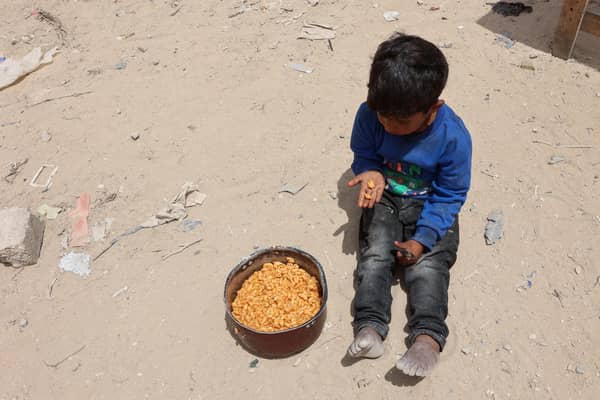 A Palestinian boy has a bite from a ration of hot food from a charity kitchen set up at the Islamic University campus in Gaza City on May 12, 2025. Israeli Prime Minister Benjamin Netanyahu said on May 12 that the release of a US-Israeli hostage announced by Hamas would not lead to a ceasefire in the Gaza Strip or the release of Palestinian detainees. (Photo by Omar AL-QATTAA / AFP) (Photo by OMAR AL-QATTAA/AFP via Getty Images)