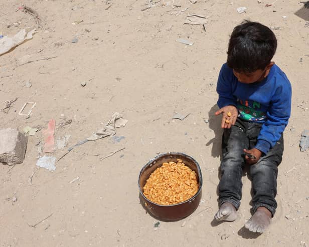 A Palestinian boy has a bite from a ration of hot food from a charity kitchen set up at the Islamic University campus in Gaza City on May 12, 2025. Israeli Prime Minister Benjamin Netanyahu said on May 12 that the release of a US-Israeli hostage announced by Hamas would not lead to a ceasefire in the Gaza Strip or the release of Palestinian detainees. (Photo by Omar AL-QATTAA / AFP) (Photo by OMAR AL-QATTAA/AFP via Getty Images)