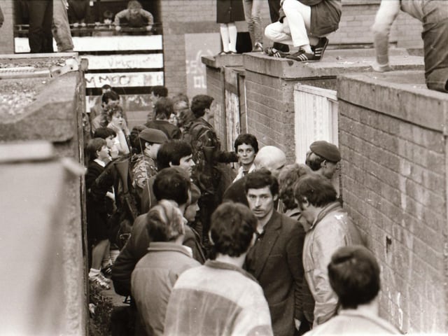 Neighbours and residents of Dove Gardens gather during a British army raid.