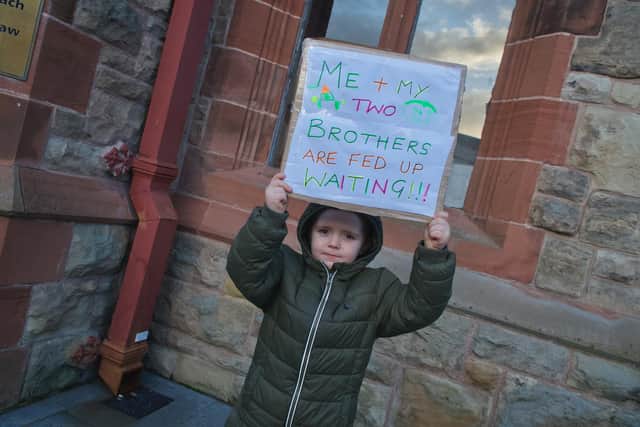 A child from one of the families who have been allocated new homes but have not yet got their keys protesting outside the Guildhall during the meeting.