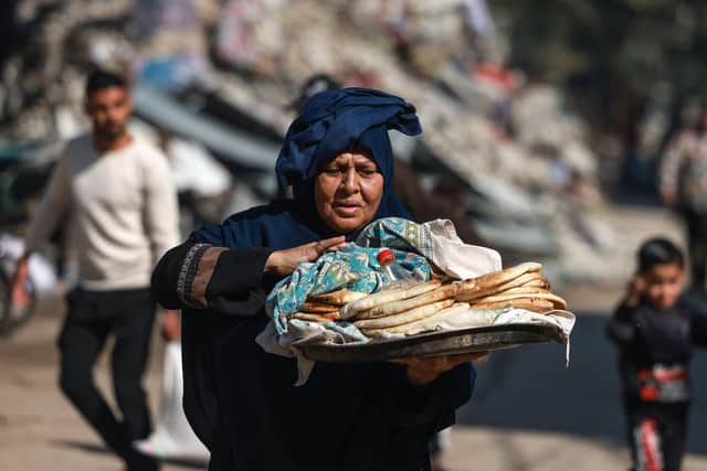 A Palestinian woman carries bread outside a UN school in Bureij in the central Gaza Strip on November 21, 2023, amid the ongoing battles between Israel and the Palestinian militant group Hamas. (Photo by MOHAMMED ABED / AFP) (Photo by MOHAMMED ABED/AFP via Getty Images)