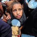 A Palestinian girl holds a container at a food distribution point in the Nuseirat camp for refugees in the central Gaza Strip on May 21, 2025. (Photo by EYAD BABA/AFP via Getty Images)