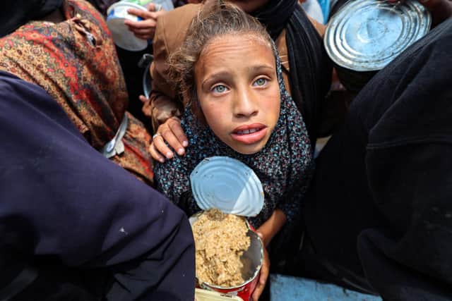 A Palestinian girl holds a container at a food distribution point in the Nuseirat camp for refugees in the central Gaza Strip on May 21, 2025. (Photo by EYAD BABA/AFP via Getty Images)