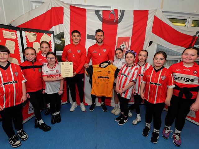 Derry City’s Ciaran Coll and Pat Hoban present Gaelscoil Eadain Mhoir with a signed shirt during their visit to the school and received a collection of poems composed by Rang 7 pupils . Photo: George Sweeney