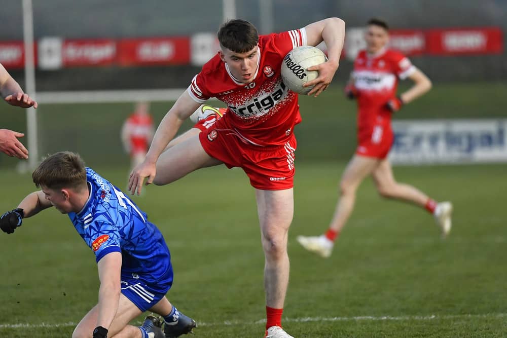 Derry’s Eamon Young hurdles over Monaghan’s Mark McCafferty. Photo: George Sweeney
