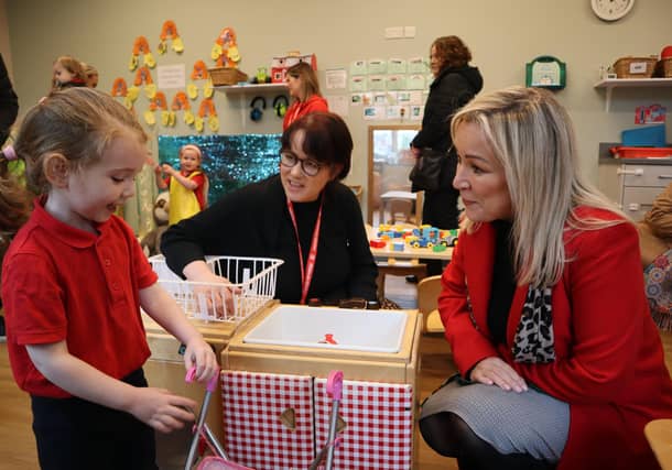 First Minister Michelle O’Neill hunkers down to chat to a little girl alongside Louise Kearney from Action for Children.