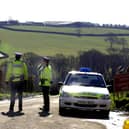 Police officers in West Devon, guard a road leading to a farm, where foot and mouth disease was confirmed on March 1, 2001. (Photo by MARTIN HAYHOW / AFP) (Photo by MARTIN HAYHOW/AFP via Getty Images)