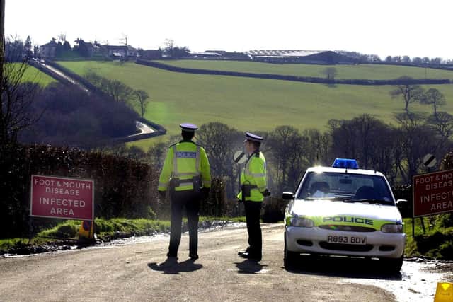Police officers in West Devon, guard a road leading to a farm, where foot and mouth disease was confirmed on March 1, 2001. (Photo by MARTIN HAYHOW / AFP) (Photo by MARTIN HAYHOW/AFP via Getty Images)