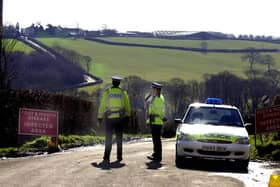 Police officers in West Devon, guard a road leading to a farm, where foot and mouth disease was confirmed on March 1, 2001. (Photo by MARTIN HAYHOW / AFP) (Photo by MARTIN HAYHOW/AFP via Getty Images)