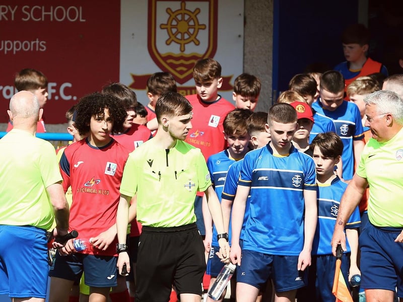 The officials lead both teams out onto the pitch at the Coleraine Showgrounds.