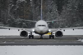A plane sits on a runway surrounded by snow