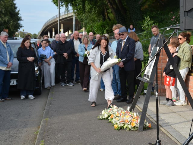 A member of the English family lays a floral wreath at the republican monument in memory of Charles English