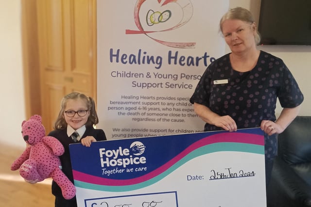 Local youngster, Katie Wilson pictured along with her much loved memory bear, Jean presenting a cheque for £200 to Healing Hearts Facilitator at Foyle Hospice, Michelle Kosky, proceeds from a Santa’s Grotto in the Glenowen Community Association.