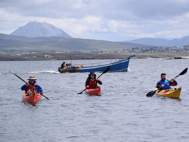 John Hubbocks, Tessa Fleming and Irial Ó Ceallaigh approach Gabhla Island with fishing boat behind them. The trio feature in Kayak Ó Thuaidh.