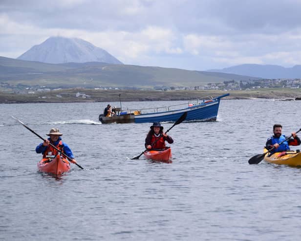 John Hubbocks, Tessa Fleming and Irial Ó Ceallaigh approach Gabhla Island with fishing boat behind them. The trio feature in Kayak Ó Thuaidh.