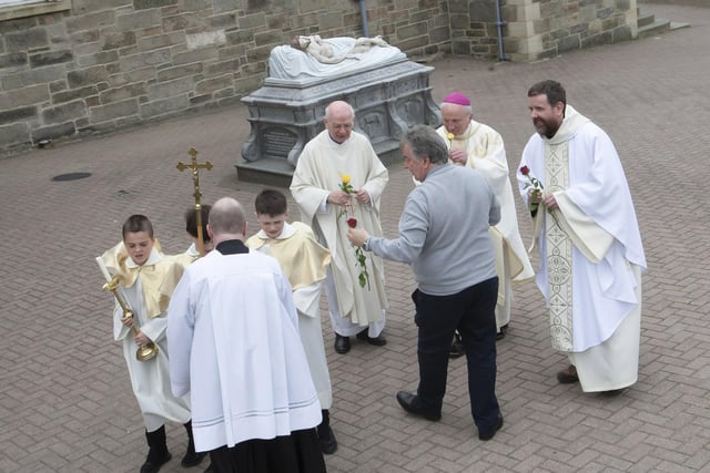 Patsy McCallion presenting roses to Bishop Dónal McKeown and the clergy who officiated at Sunday’s Mass in the Long Tower Church.