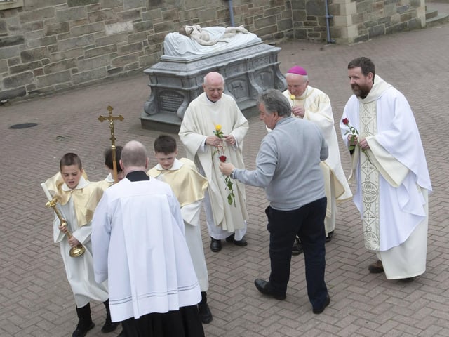 Patsy McCallion presenting roses to Bishop Dónal McKeown and the clergy who officiated at Sunday’s Mass in the Long Tower Church.