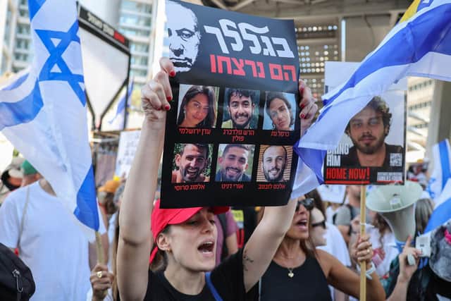 A protester lifts a placard bearing portraits of six Israeli hostages whose bodies were recovered by the army from the southern Gaza Strip, during a rally by families and supporters of the hostages in Tel Aviv on September 2, 2024, amid the ongoing conflict in the Gaza Strip between Israel and the Palestinian militant Hamas movement. (Photo by Jack GUEZ / AFP) (Photo by JACK GUEZ/AFP via Getty Images)