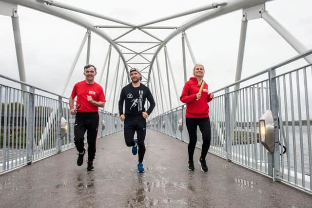 Waterside Half Marathon reigning senior men’s champion Kyle Doherty from City of Derry Spartans promoting the event on the Pennyburn Footbridge with Star Running Club members Patrick McCarry and Louise Wilkinson.