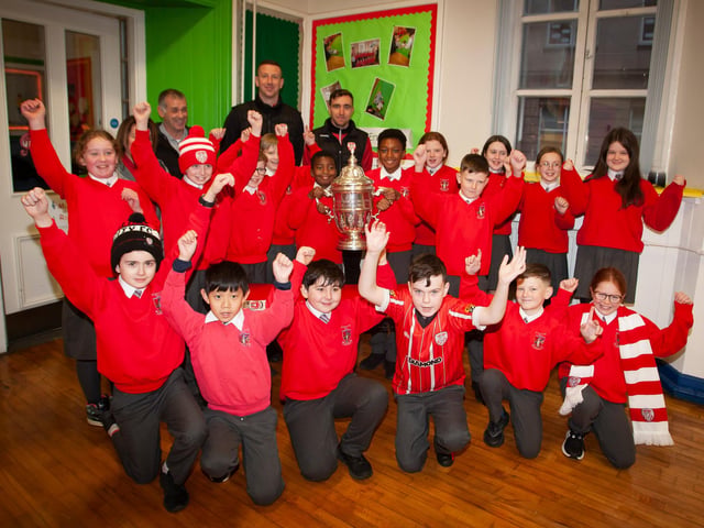 P7 pupils at St. Eugene’s PS show their support for Derry City on Monday last as players Shane McEleney and Joe Thompson brought the FAI Cup to the school.