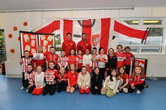 Pupils from Gaelscoil Eadain Mhoir pictured with Derry City’s Ciaran Coll and Pat Hoban during their visit to the school on Monday morning. Photo: George Sweeney