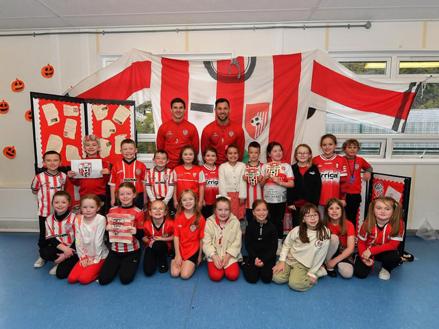 Pupils from Gaelscoil Eadain Mhoir pictured with Derry City’s Ciaran Coll and Pat Hoban during their visit to the school on Monday morning. Photo: George Sweeney