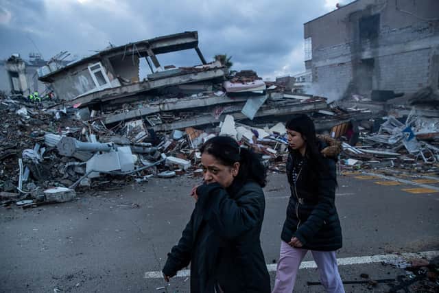 HATAY, TURKEY - FEBRUARY 07: Women walk past the scene of a collapsed building on February 07, 2023 in Iskenderun, Turkey. A 7.8-magnitude earthquake hit near Gaziantep, Turkey, in the early hours of Monday, followed by another 7.5-magnitude tremor just after midday. The quakes caused widespread destruction in southern Turkey and northern Syria and were felt in nearby countries. (Photo by Burak Kara/Getty Images)