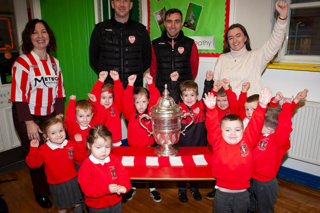 Nursery pupils at St. Eugene’s PS show their support for Derry City on Monday last as players Shane McEleney and Joe Thompson brought the FAI Cup to the school.