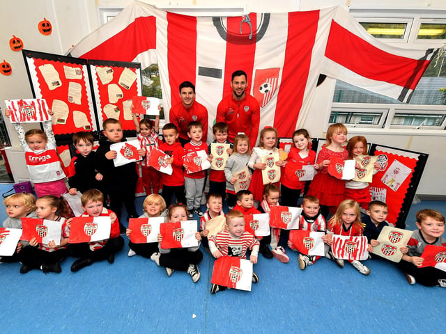 Pupils from Gaelscoil Eadain Mhoir pictured with Derry City’s Ciaran Coll and Pat Hoban during their visit to the school on Monday morning. Photo: George Sweeney