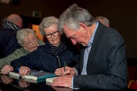 Denis Bradley signs copies of his book ‘Peace Comes Dropping Slowly’, at the official launch in St Columb’s Hall on Thursday evening last. Photo: George Sweeney