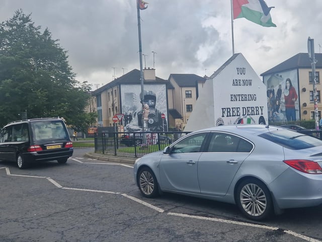 Nell McCafferty's funeral cortege passes Free Derry Corner.