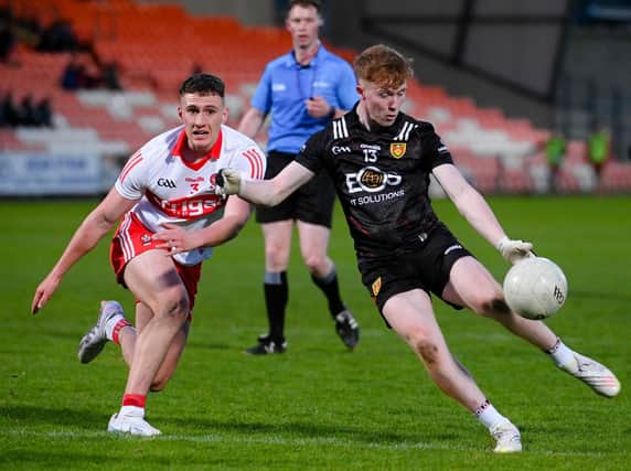 Down's Oisin Savage thumps a second half point over the bar despite pressure from Derry's Jody McDermott. RS2318405