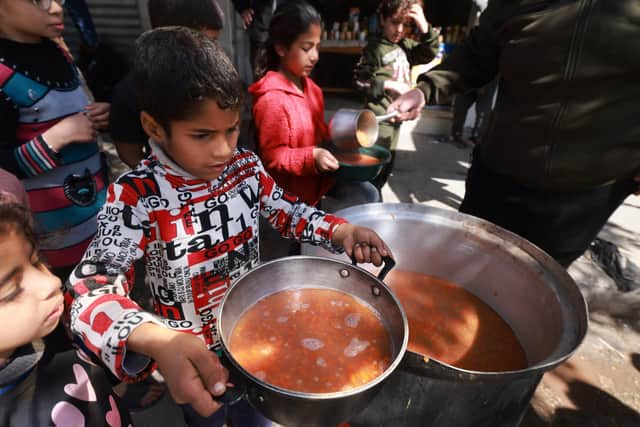 Palestinian children receive cooked food rations as part of a volunteer youth initiative in Rafah in the southern Gaza Strip, on March 5, 2024, amid widespread hunger in the besieged Palestinian territory as the conflict between Israel and the Palestinian militant group Hamas continues. (Photo by MOHAMMED ABED / AFP) (Photo by MOHAMMED ABED/AFP via Getty Images)