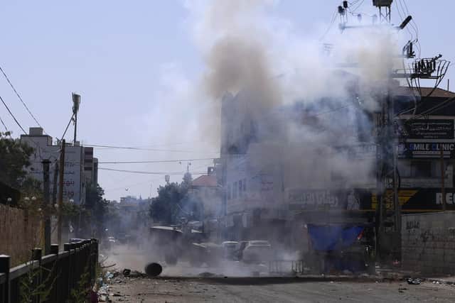 An Israeli armoured vehicle is stationed amid billowing smoke during an ongoing military operation in Jenin city in the occupied West Bank on July 4, 2023. Israel's biggest military operation for years in the occupied West Bank continued for a second day on July 4, leaving at least 10 Palestinians dead and forcing thousands to flee their homes as the government said it struck "with great strength" the militant stronghold. (Photo by Jaafar ASHTIYEH / AFP) (Photo by JAAFAR ASHTIYEH/AFP via Getty Images)