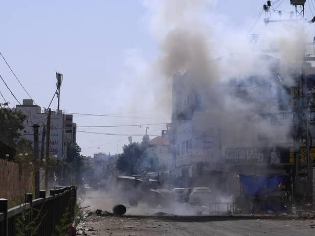An Israeli armoured vehicle is stationed amid billowing smoke during an ongoing military operation in Jenin city in the occupied West Bank on July 4, 2023. Israel's biggest military operation for years in the occupied West Bank continued for a second day on July 4, leaving at least 10 Palestinians dead and forcing thousands to flee their homes as the government said it struck "with great strength" the militant stronghold. (Photo by Jaafar ASHTIYEH / AFP) (Photo by JAAFAR ASHTIYEH/AFP via Getty Images)