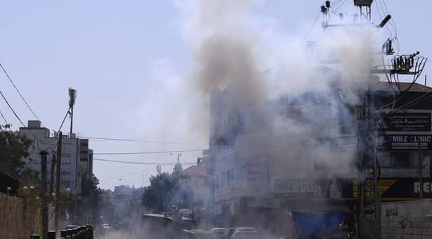 An Israeli armoured vehicle is stationed amid billowing smoke during an ongoing military operation in Jenin city in the occupied West Bank on July 4, 2023. Israel's biggest military operation for years in the occupied West Bank continued for a second day on July 4, leaving at least 10 Palestinians dead and forcing thousands to flee their homes as the government said it struck "with great strength" the militant stronghold. (Photo by Jaafar ASHTIYEH / AFP) (Photo by JAAFAR ASHTIYEH/AFP via Getty Images)