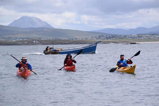 John Hubbocks, Tessa Fleming and Irial Ó Ceallaigh approach Gabhla Island with fishing boat behind them. The trio feature in Kayak Ó Thuaidh.