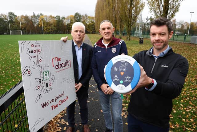 John Deery (centre) from Eglinton survived a cardiac arrest at this year’s Belfast Marathon thanks to a life-saving defibrillator and CPR performed by Peter O’Hare (right holding the defib). John and Peter are pictured alongside Head of British Heart Foundation NI’s Fearghal McKinney and are backing the leading heart charity’s campaign to help create a lifesaving map of 100,000 UK-wide defibrillator registrations, ensuring more lives can be saved in emergencies. The Circuit is the national defibrillator network which maps defibrillators across the UK so that ambulance services can direct bystanders to the nearest registered defibrillator if they see somebody having a cardiac arrest.