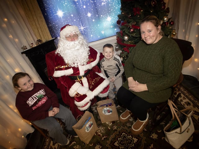 One of the many families getting a photo and collecting a present from Santa on Saturday at Derry Credit Union. : .